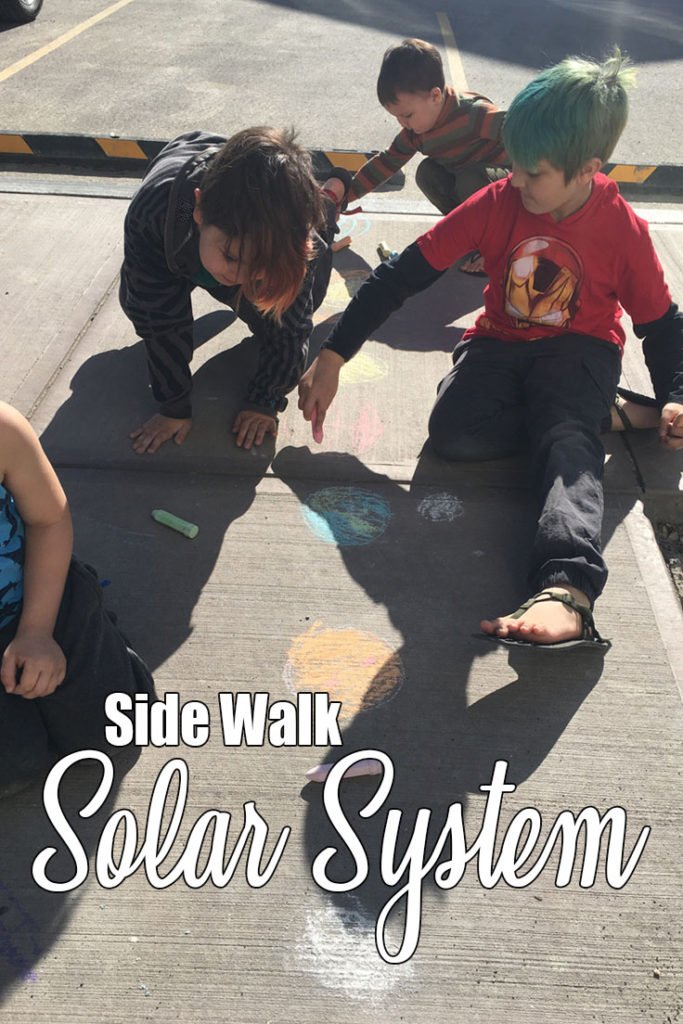 Using colourful chalk to make a model of our solar system on the sidewalk. All the planets (Mercury, Venus, Earth, Mars, Jupiter, Saturn, Uranus, Neptune), their moons and the sun are included.