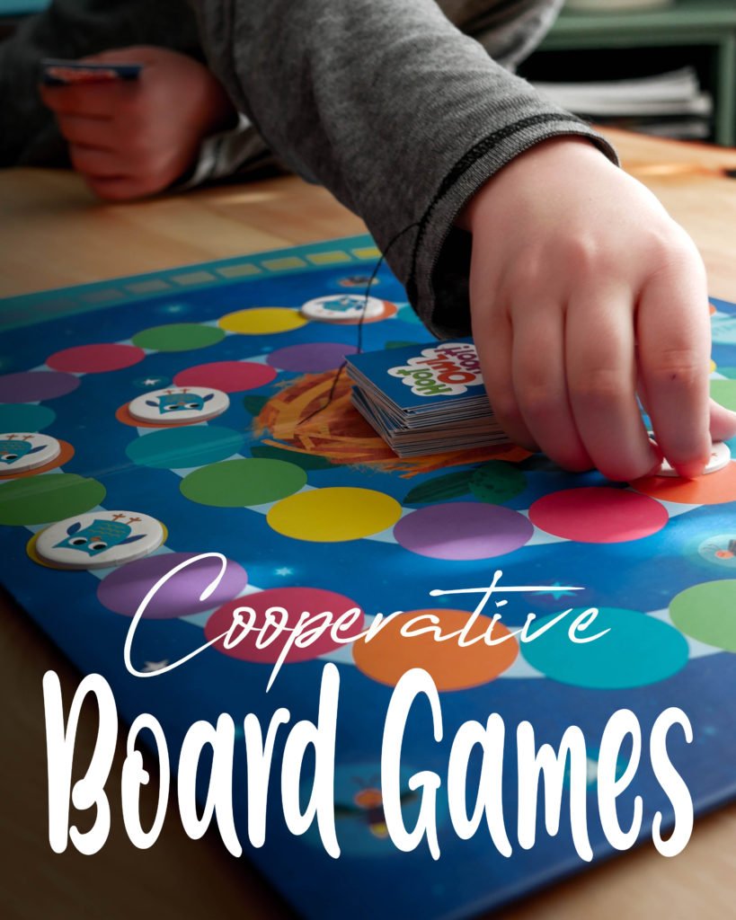 child's hand reaching for a piece as they play a cooperative board game