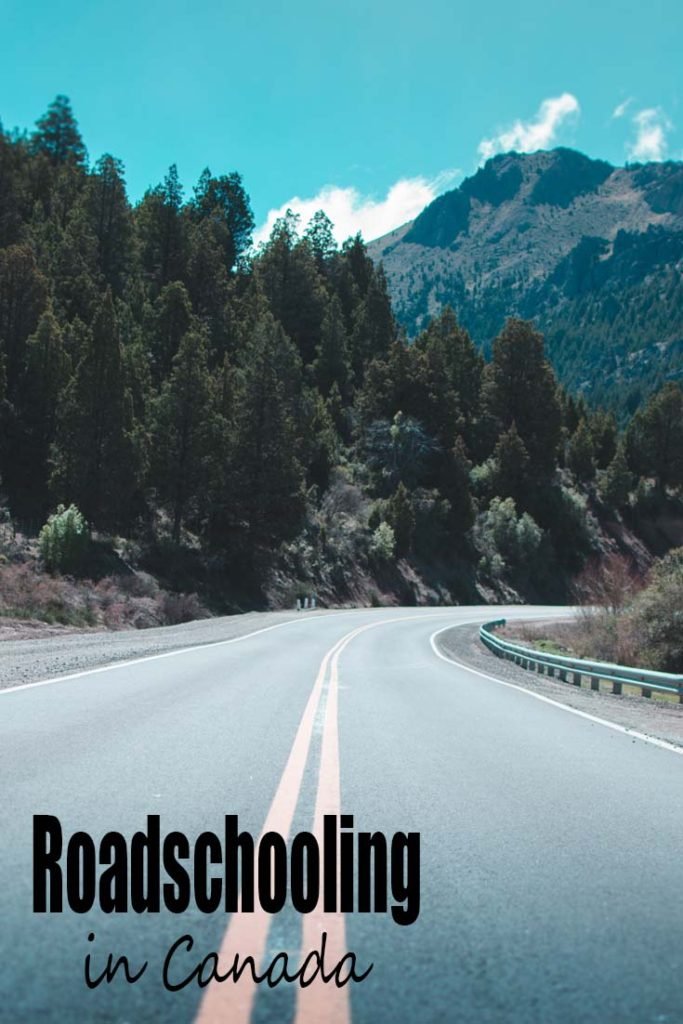 A windy two lane highway with evergreen trees along the side of the road and mountains in the distance.  "Roadschooling in Canada" written on the bottom left.