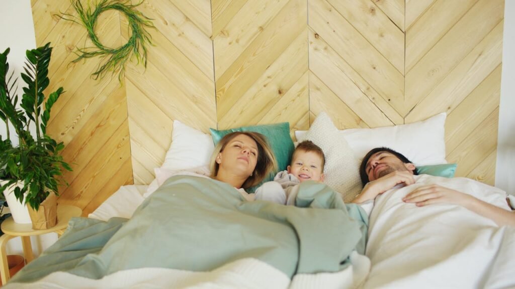 two parents laying in bed, napping with their toddler. The Connection Between Sleep and Emotional Well-Being for Parents