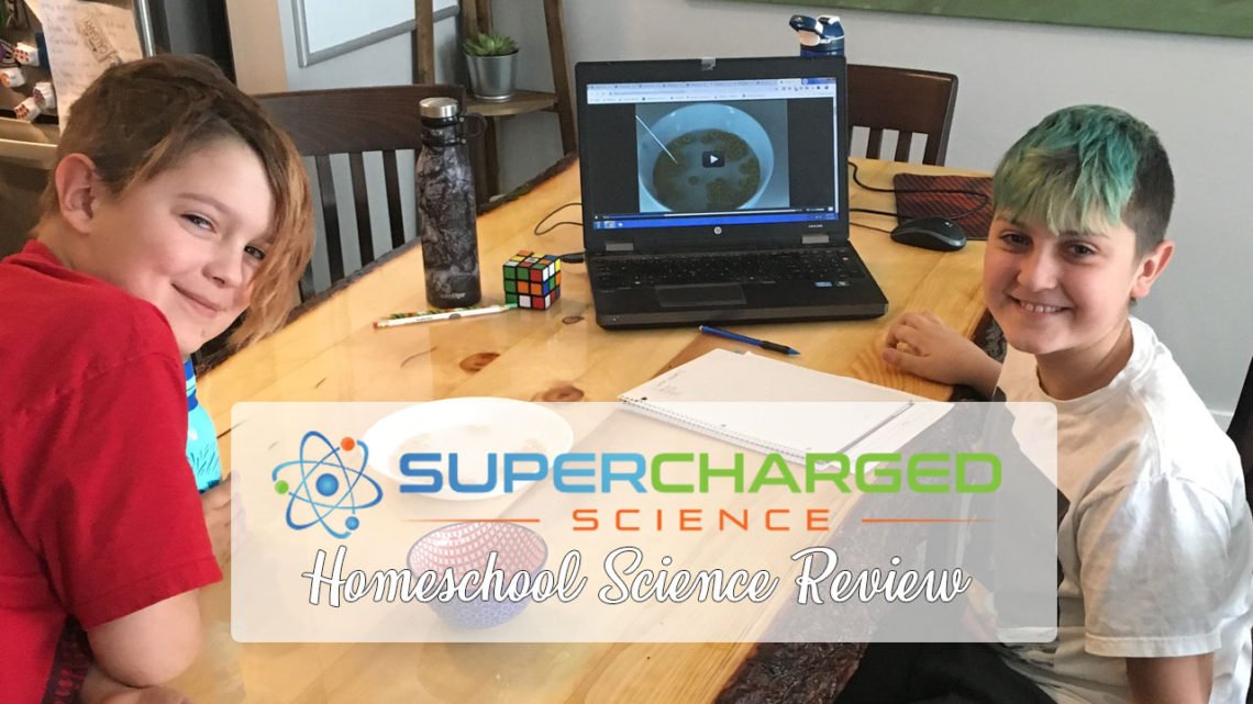 Two boys smiling as they work on a science experiment from Supercharged Science. you looking for a homeschool science program? Check out this review for Supercharged Science - an interactive science program with lots of experiments!