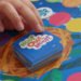 child's hand reaches for a card while playing a cooperative board game