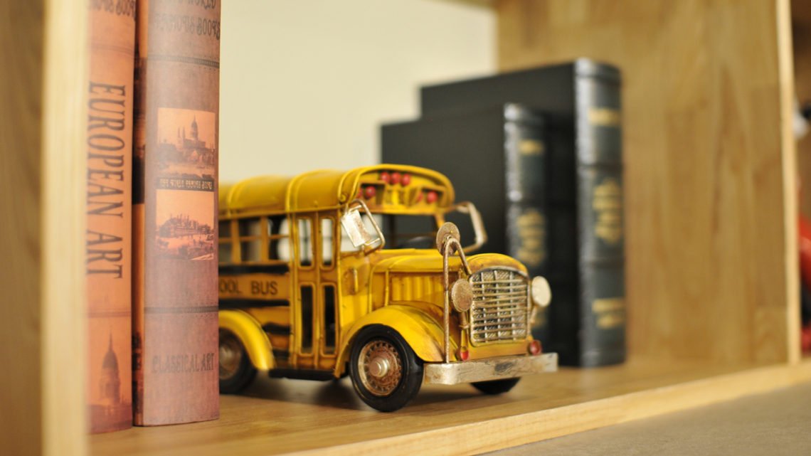 toy school bus sits on a shelf surrounded by old books