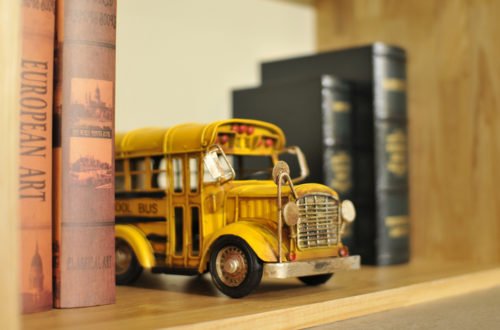 toy school bus sits on a shelf surrounded by old books