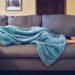 Mom lays on a gray couch, covered in a fuzzy blue blanket.