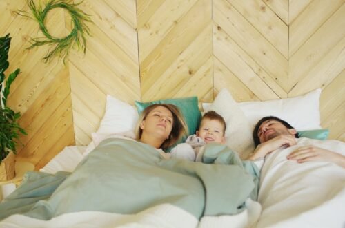 two parents laying in bed, napping with their toddler. The Connection Between Sleep and Emotional Well-Being for Parents